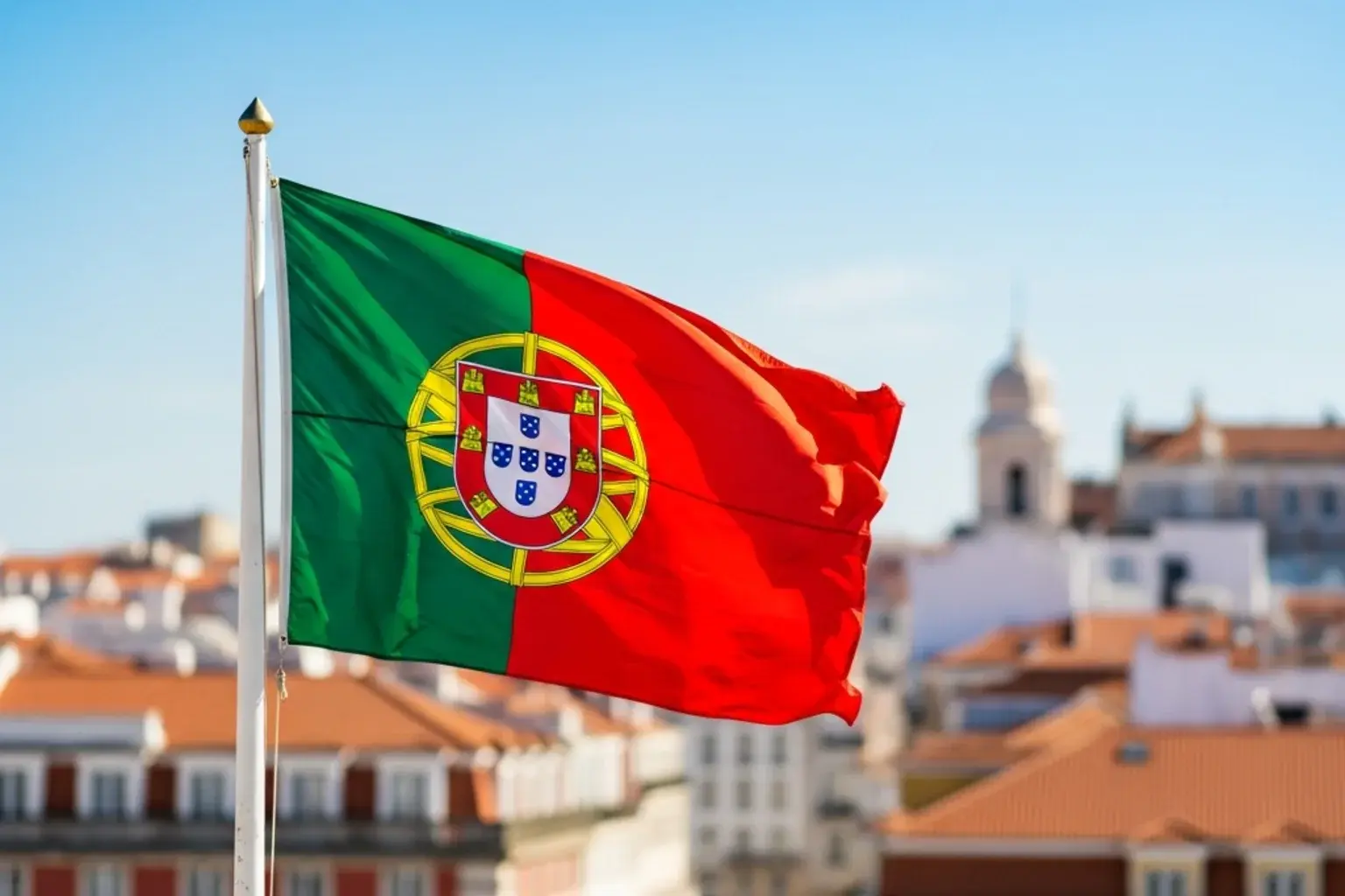 Bandeira de Portugal ao vento com edificios de Lisboa desfocados ao fundo